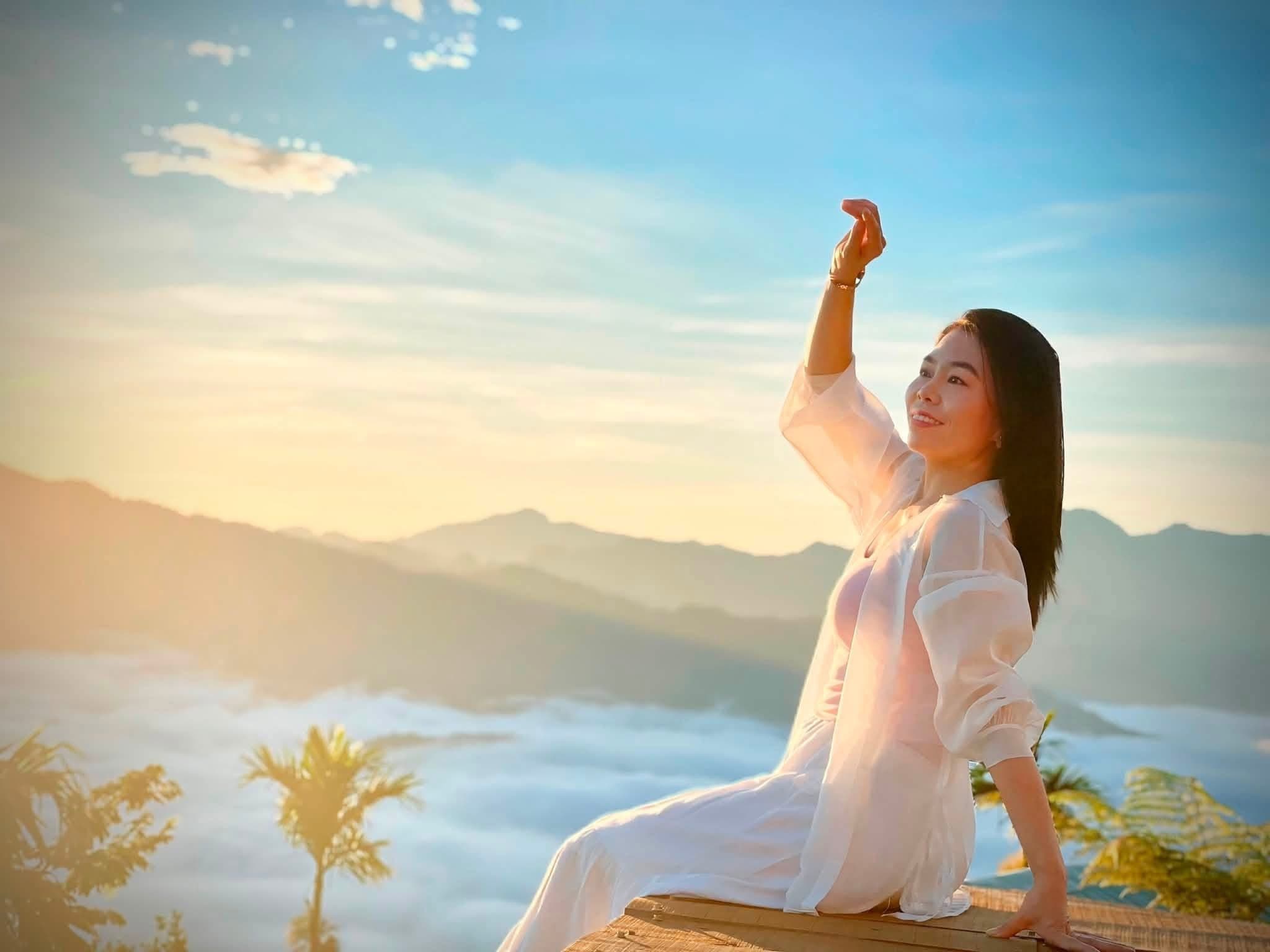 Cô gái áo trắng tạo dáng bên biển mây, vươn tay lên trời xanh