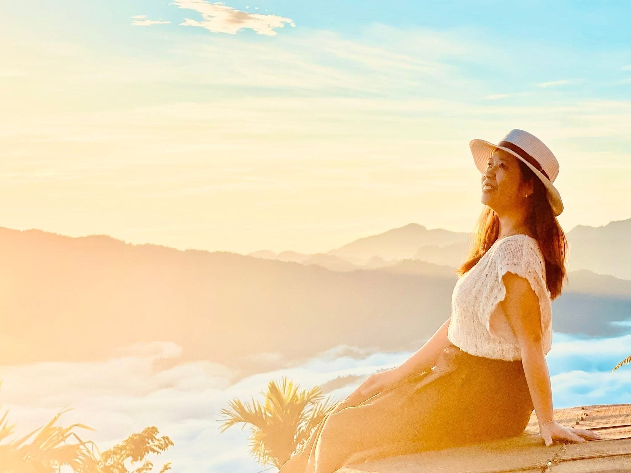 Khách nữ đội nón ngồi ngắm hoàng hôn vàng rực trên biển mây