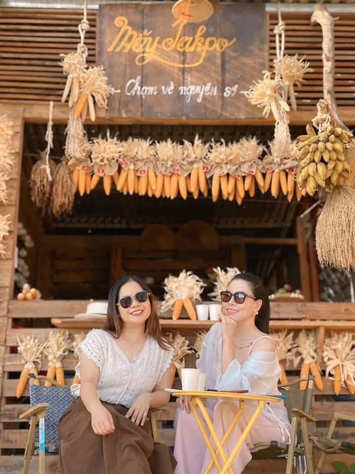 Hai người bạn ngồi cà phê dưới bảng hiệu Mây Takpo