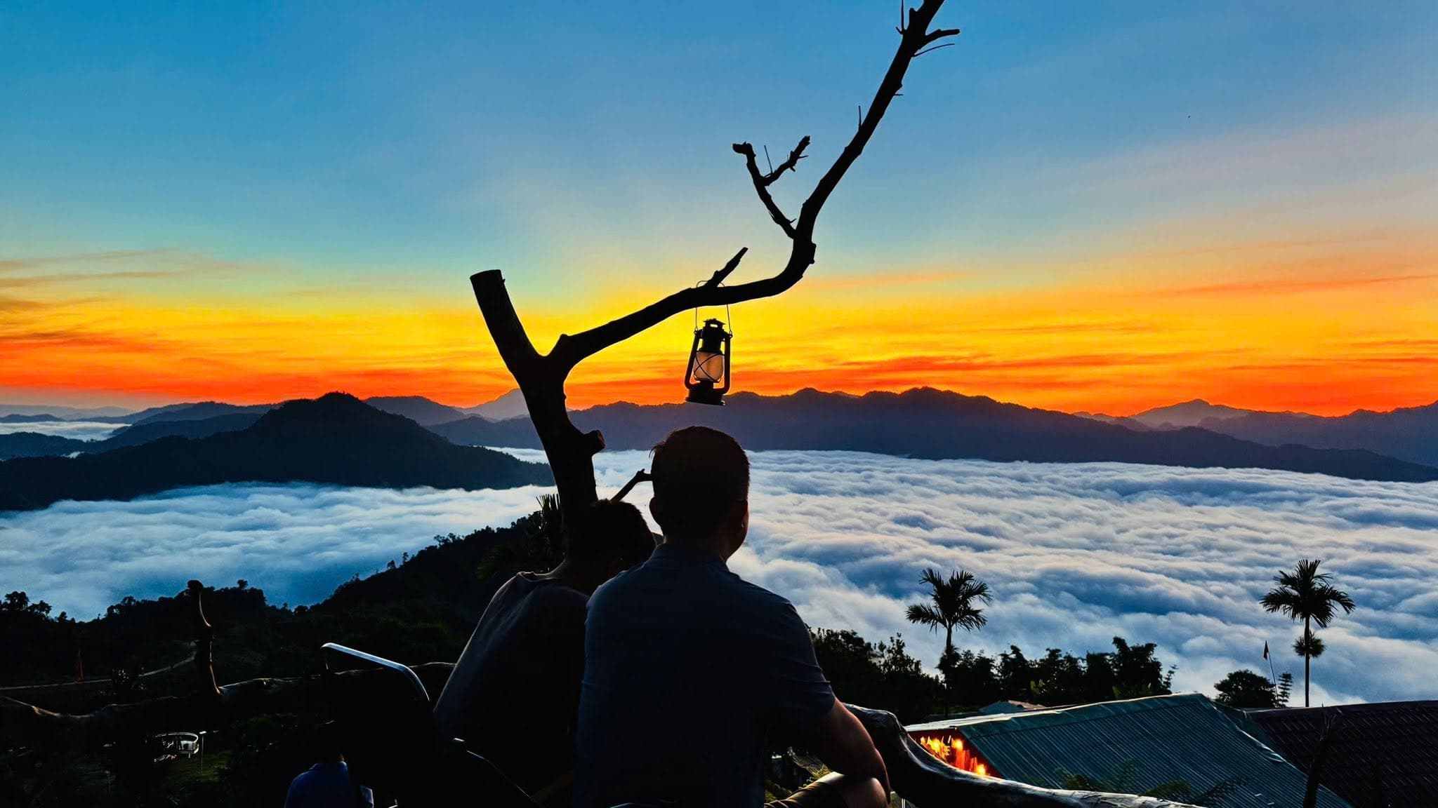 Hai du khách ngồi bên nhau ngắm hoàng hôn trên biển mây