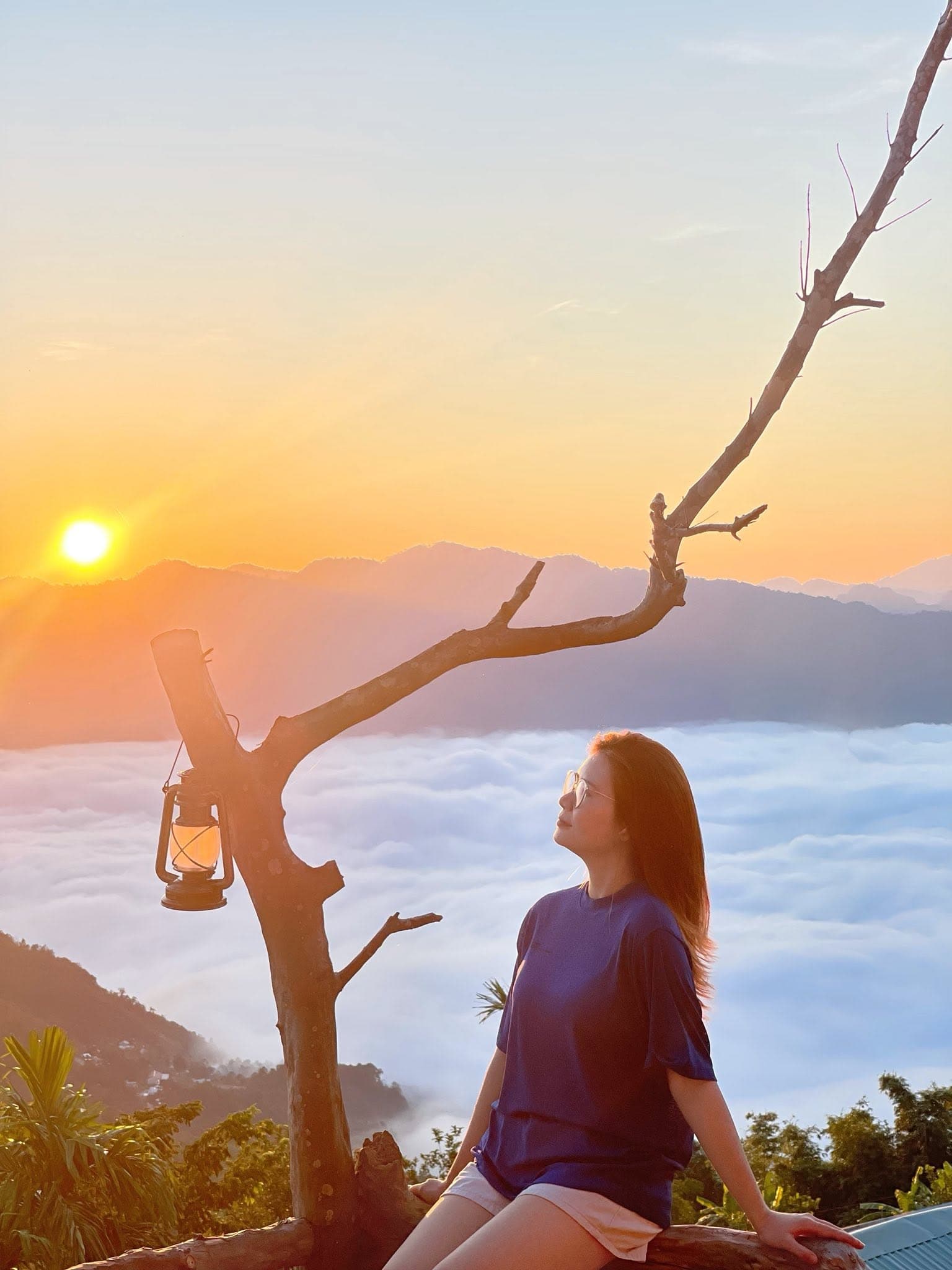 Cô gái ngồi ngắm bình minh bên đèn bão, biển mây Mây Takpo