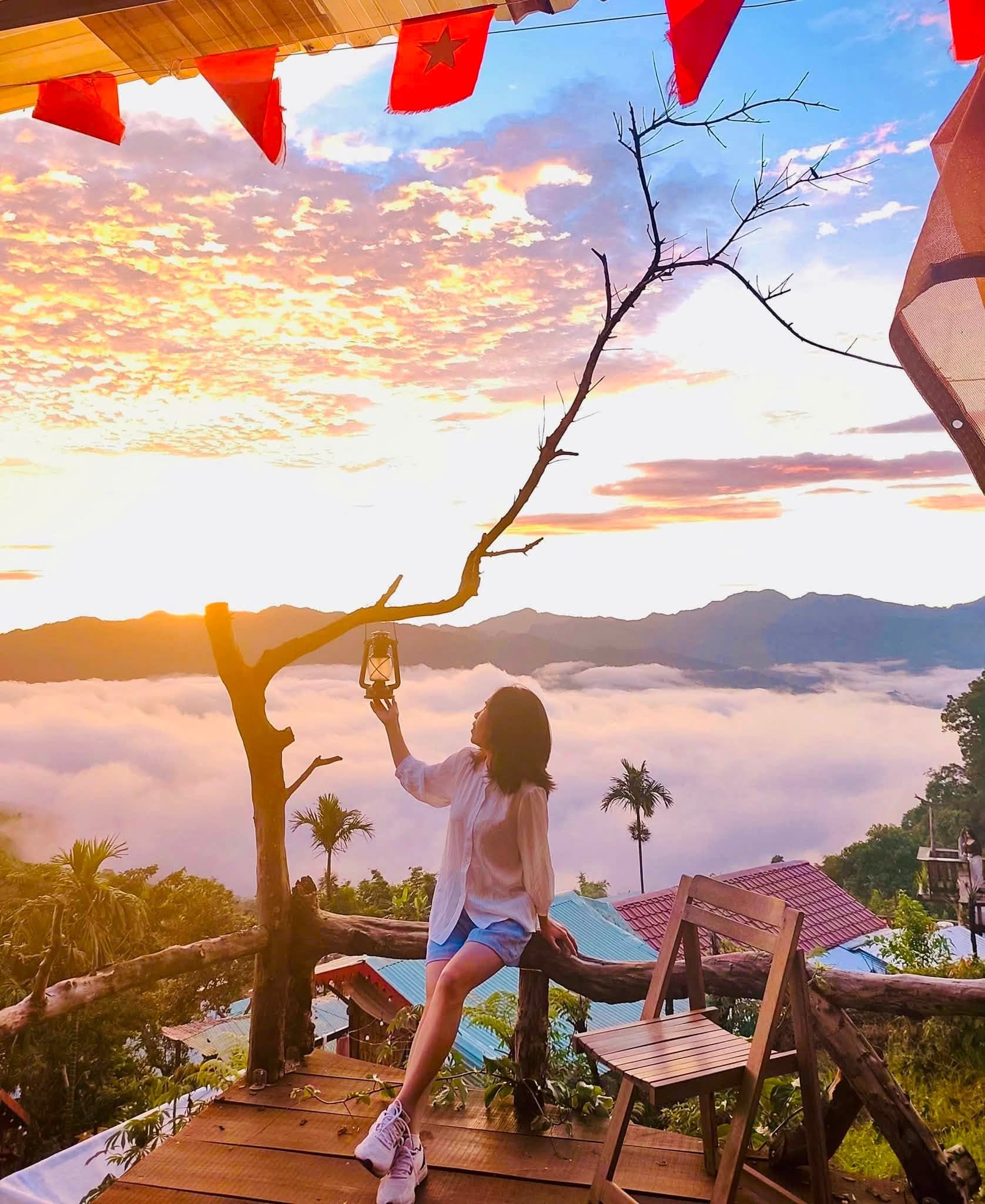 Cô gái với tay chạm đèn lồng dưới cờ đỏ lúc hoàng hôn