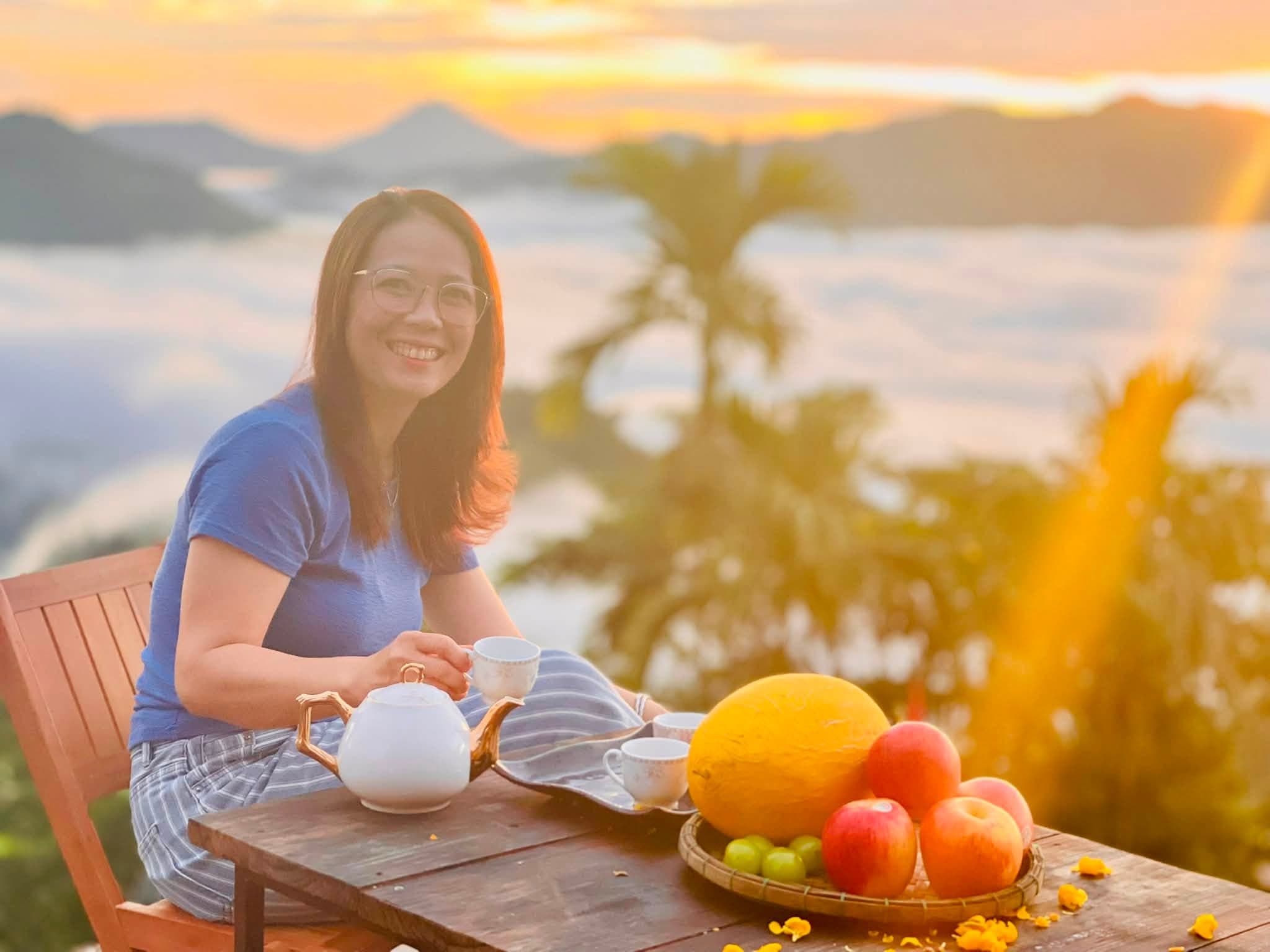 Rót trà bên đĩa trái cây, hoàng hôn biển mây phía xa